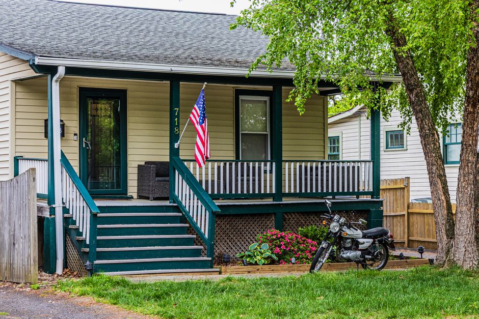 Inviting front porch of a beautifully maintained bungalow in Memphis, bathed in bright sunlight, representing an attractiv...